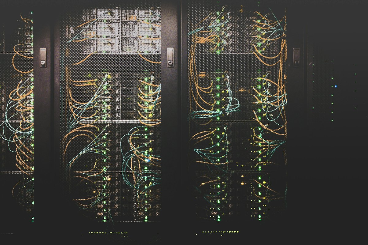 Server racks in a dark data centre, cabling lit by status lights
